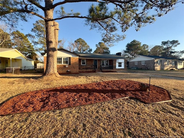 ranch-style house featuring brick siding, a chimney, and fence