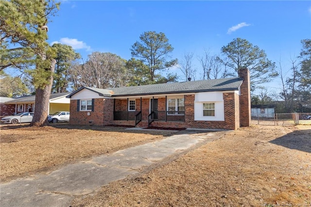 ranch-style house featuring a chimney, fence, a porch, and brick siding