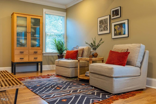 sitting room featuring ornamental molding, baseboards, and wood finished floors