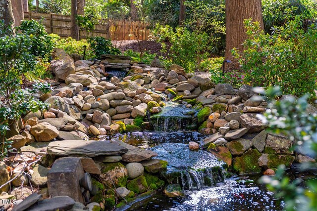 exterior space with a small pond and fence