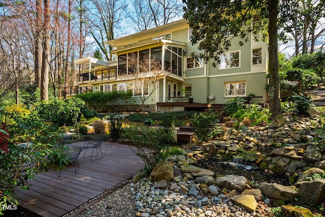 rear view of property featuring a sunroom and a wooden deck