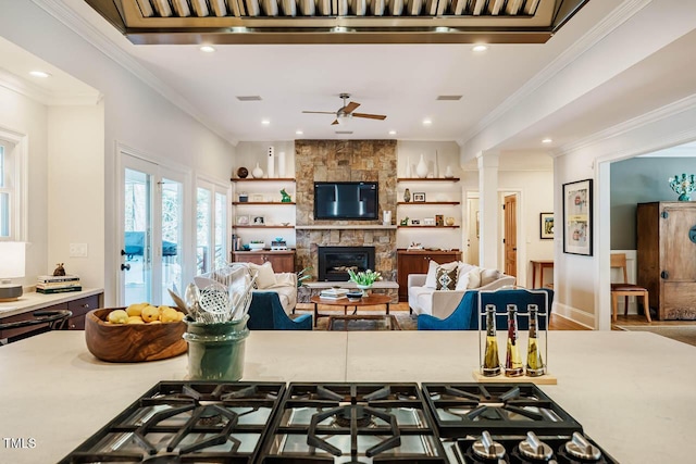 kitchen with a stone fireplace, ornamental molding, a ceiling fan, and light countertops