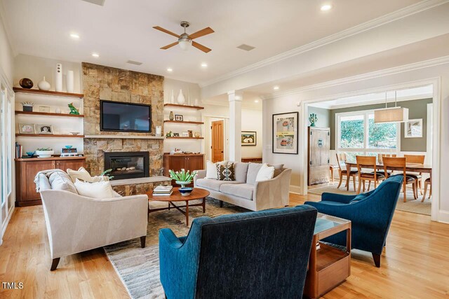 living area with light wood-style floors, ornamental molding, and a fireplace