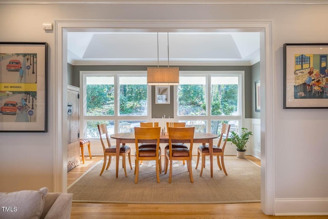 dining space with a wealth of natural light, a wainscoted wall, light wood-style flooring, and crown molding