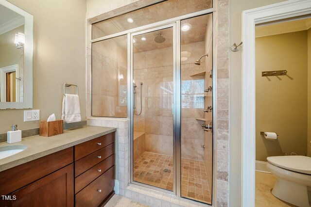 full bath featuring vanity, baseboards, a shower stall, crown molding, and toilet