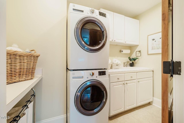 washroom featuring baseboards, cabinet space, and stacked washing maching and dryer