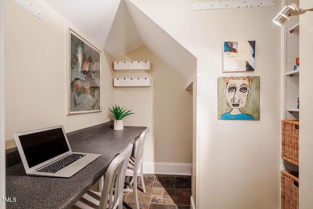 office with vaulted ceiling, baseboards, and stone finish flooring