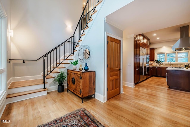 stairs with recessed lighting, baseboards, wood finished floors, and crown molding