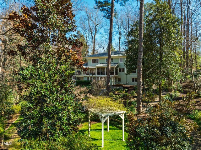 rear view of house featuring a lawn, a deck, a pergola, and a sunroom