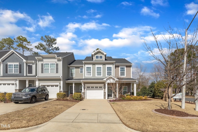 view of front facade featuring driveway, stone siding, a shingled roof, and a garage