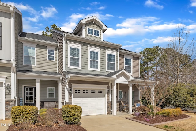 view of front of house with an attached garage, covered porch, stone siding, and concrete driveway