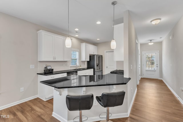 kitchen with a breakfast bar, wood finished floors, white cabinetry, and stainless steel fridge with ice dispenser