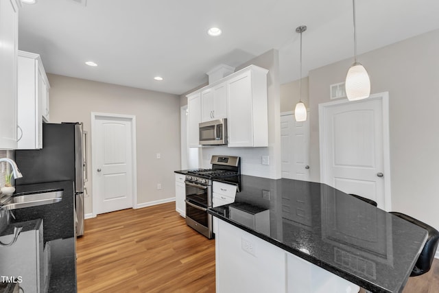 kitchen with stainless steel appliances, light wood-style floors, white cabinetry, a sink, and recessed lighting