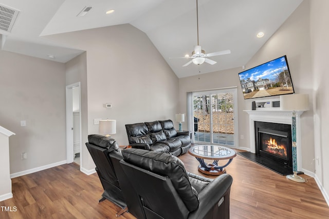 living room with visible vents, a glass covered fireplace, ceiling fan, wood finished floors, and baseboards