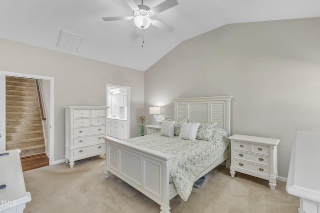 bedroom featuring baseboards, light colored carpet, ceiling fan, ensuite bathroom, and vaulted ceiling