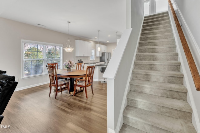 dining space featuring light wood finished floors, recessed lighting, visible vents, stairway, and baseboards