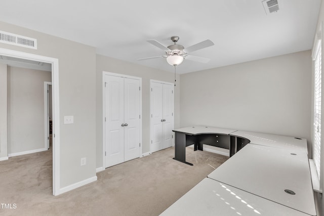 laundry area featuring baseboards, visible vents, a ceiling fan, and light colored carpet