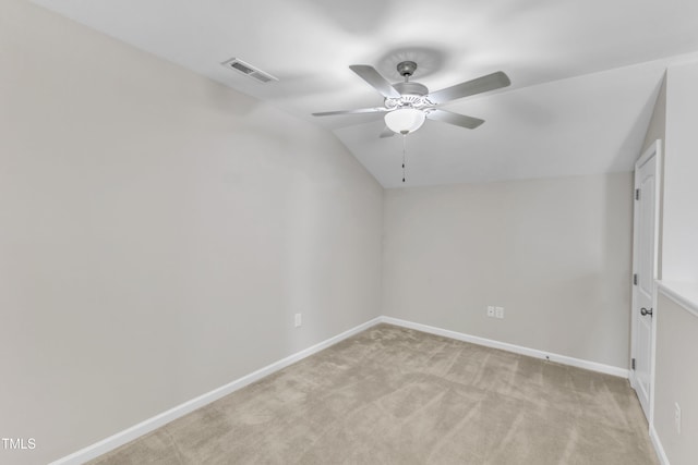 spare room featuring lofted ceiling, baseboards, visible vents, and light colored carpet