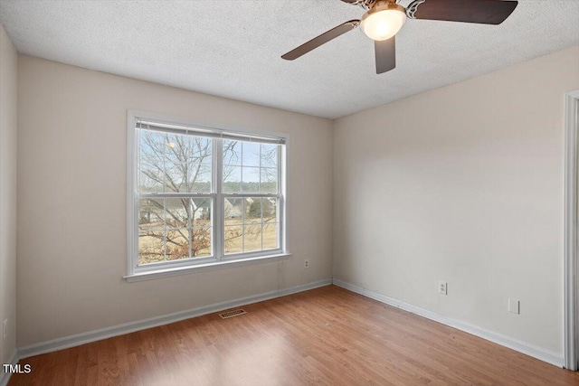 spare room with visible vents, a textured ceiling, baseboards, and wood finished floors