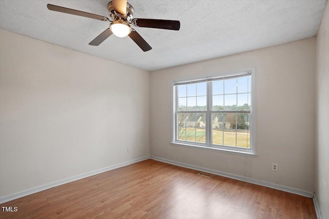 unfurnished room featuring baseboards, a textured ceiling, visible vents, and wood finished floors