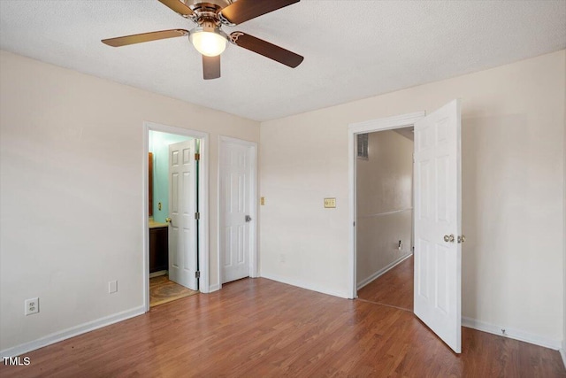 unfurnished bedroom with a ceiling fan, a textured ceiling, baseboards, and wood finished floors