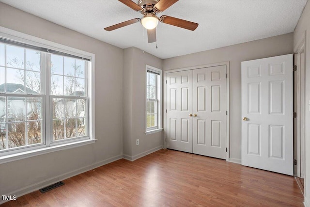 unfurnished bedroom with light wood finished floors, multiple windows, and visible vents