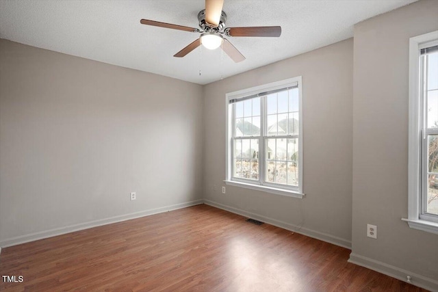 spare room featuring ceiling fan, wood finished floors, visible vents, and baseboards