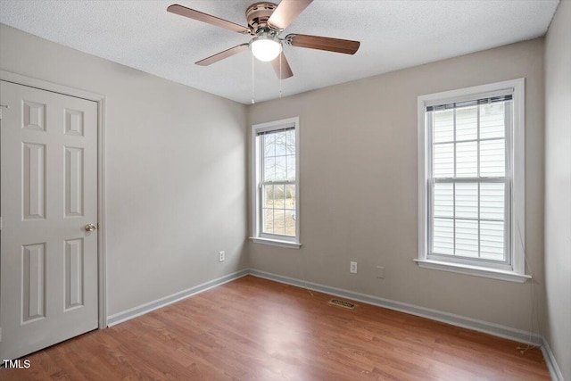 unfurnished room with baseboards, visible vents, a textured ceiling, and light wood finished floors