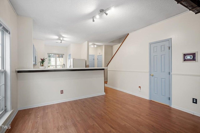 empty room featuring a textured ceiling, baseboards, and wood finished floors