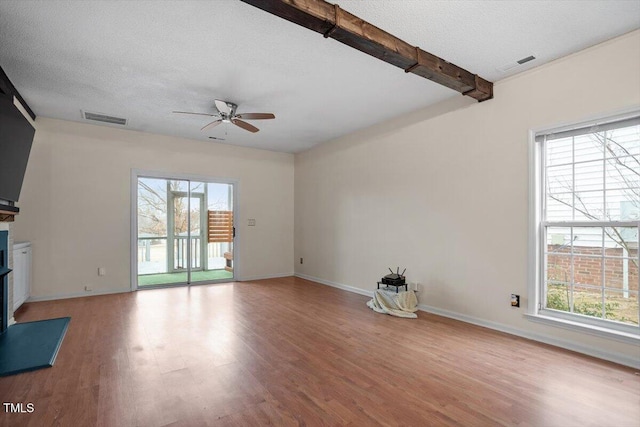 unfurnished living room with a textured ceiling, a wealth of natural light, and visible vents