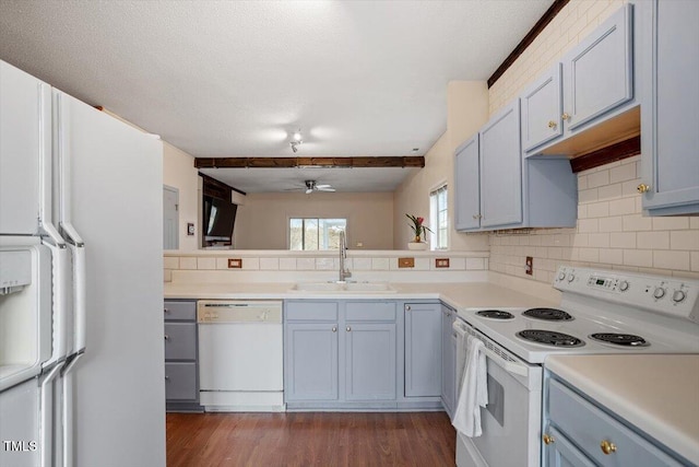 kitchen with light countertops, backsplash, dark wood-type flooring, a sink, and white appliances