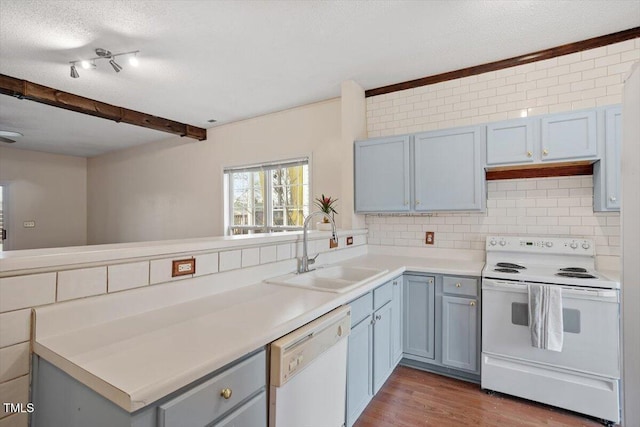 kitchen featuring white appliances, backsplash, a sink, and light countertops