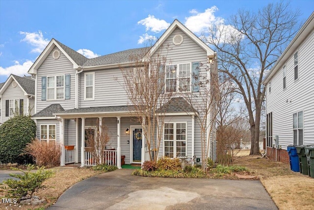 traditional home featuring a porch and roof with shingles