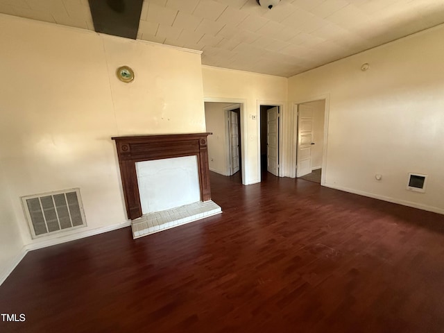 unfurnished living room featuring baseboards, visible vents, a fireplace with raised hearth, and dark wood-style flooring