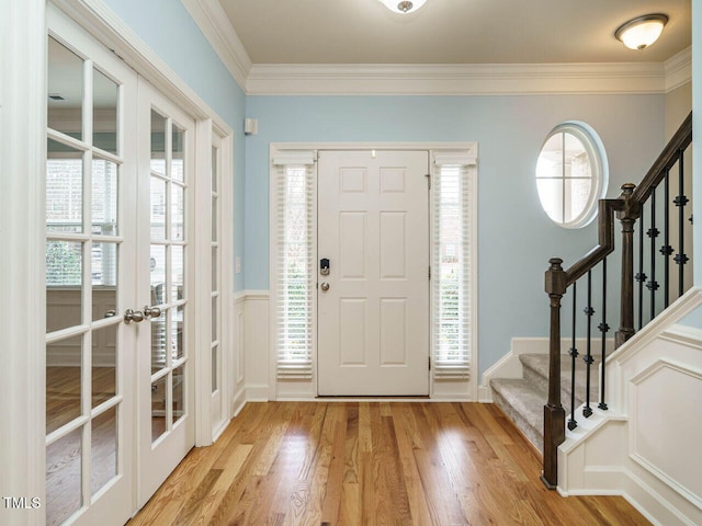 entrance foyer featuring crown molding, stairway, plenty of natural light, and light wood-style floors