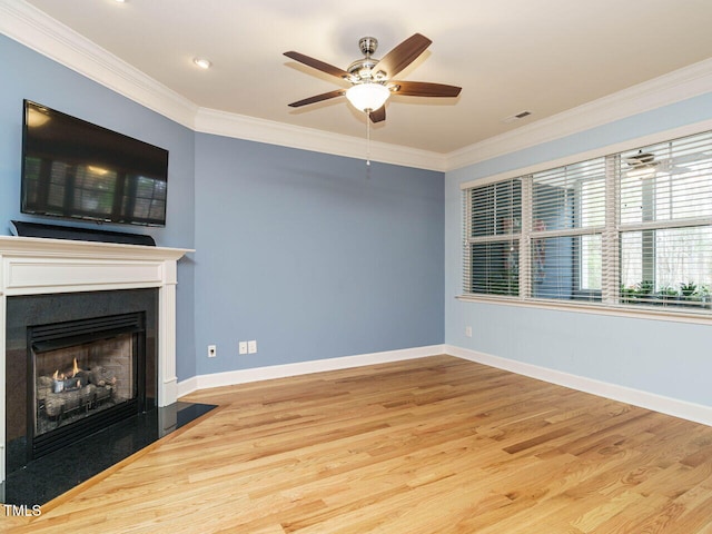 unfurnished living room with wood finished floors, visible vents, baseboards, a warm lit fireplace, and ornamental molding