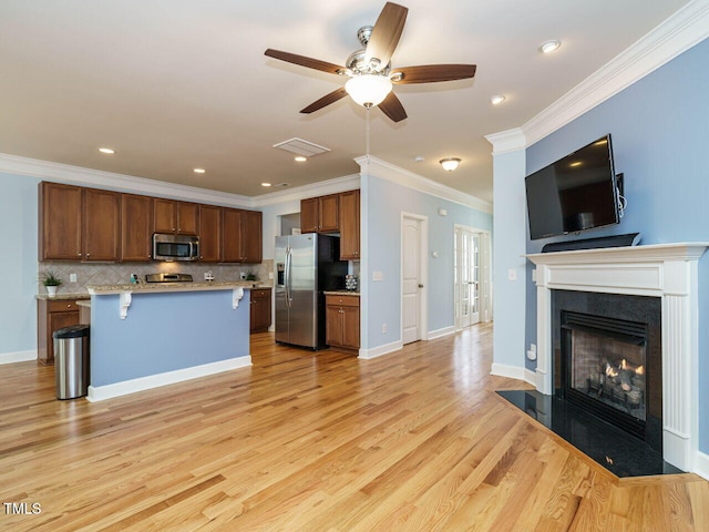 kitchen with light wood-type flooring, a kitchen bar, open floor plan, appliances with stainless steel finishes, and light countertops