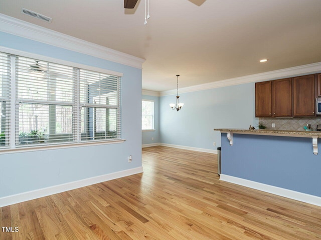 kitchen with visible vents, crown molding, a breakfast bar, decorative backsplash, and ceiling fan with notable chandelier