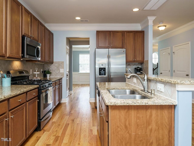 kitchen with visible vents, light wood-type flooring, an island with sink, appliances with stainless steel finishes, and a sink