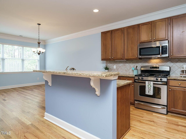 kitchen with a kitchen bar, light wood-type flooring, appliances with stainless steel finishes, and ornamental molding