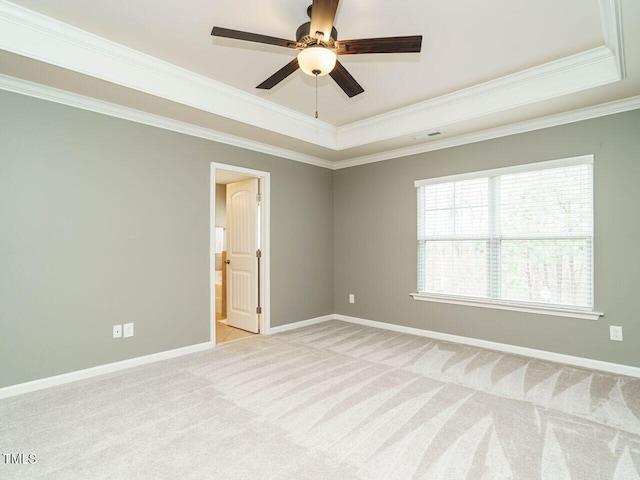 spare room with a tray ceiling, light colored carpet, baseboards, and ornamental molding