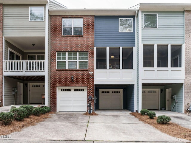 back of property featuring brick siding, driveway, and a garage