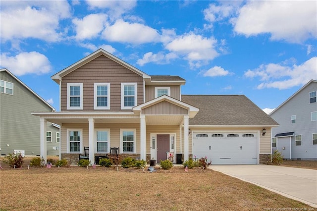 view of front of property featuring a porch, an attached garage, driveway, stone siding, and a front lawn