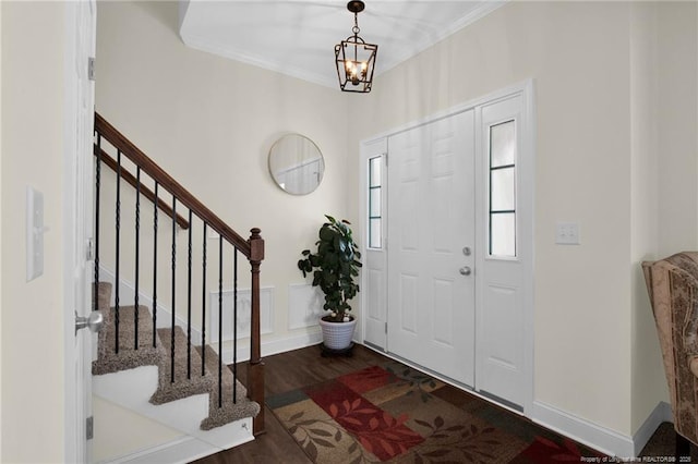 foyer featuring stairs, ornamental molding, wood finished floors, and an inviting chandelier