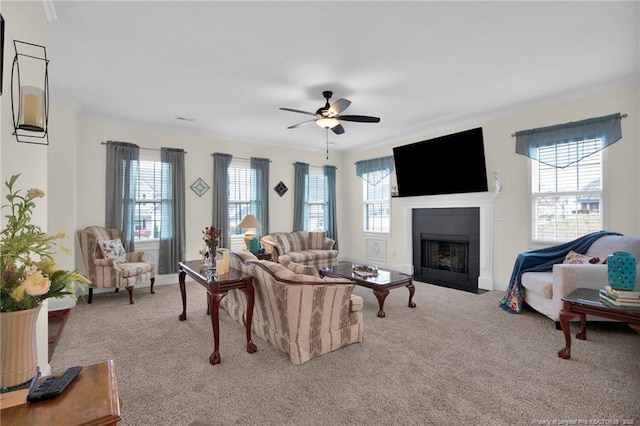 carpeted living room with ceiling fan, crown molding, baseboards, and a tiled fireplace