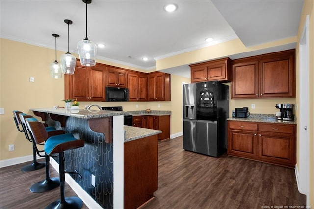 kitchen with a breakfast bar, black microwave, stainless steel fridge, range, and a peninsula