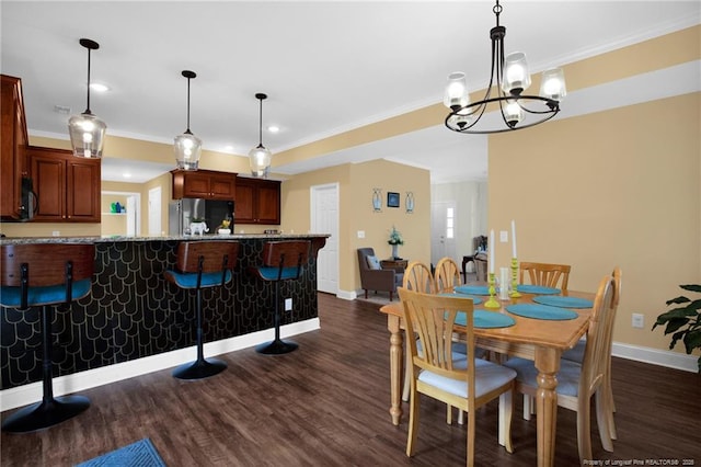 dining area featuring dark wood-style floors, baseboards, ornamental molding, and a notable chandelier