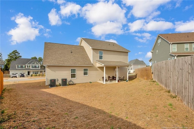 rear view of property featuring roof with shingles, a patio area, cooling unit, and fence