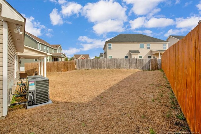 view of yard with central air condition unit, a fenced backyard, and a residential view