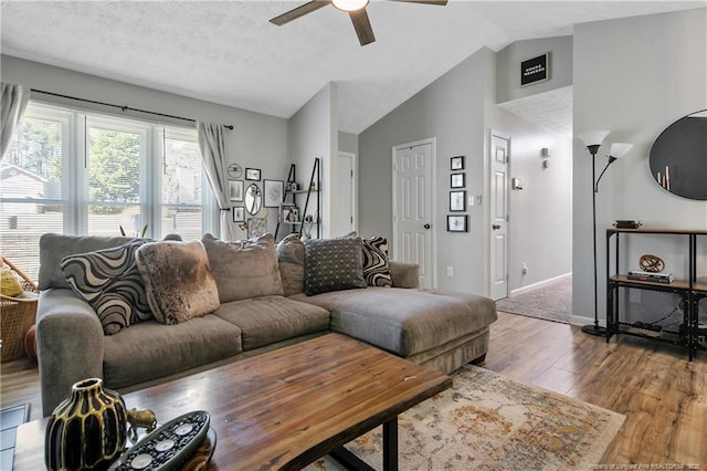 living area featuring lofted ceiling, a ceiling fan, a textured ceiling, wood finished floors, and baseboards